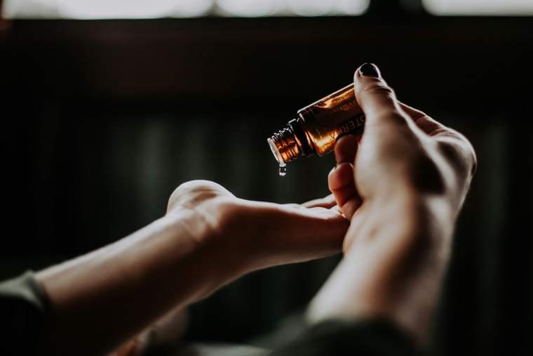 Essential oil drop falling into a hand for aromatherapy